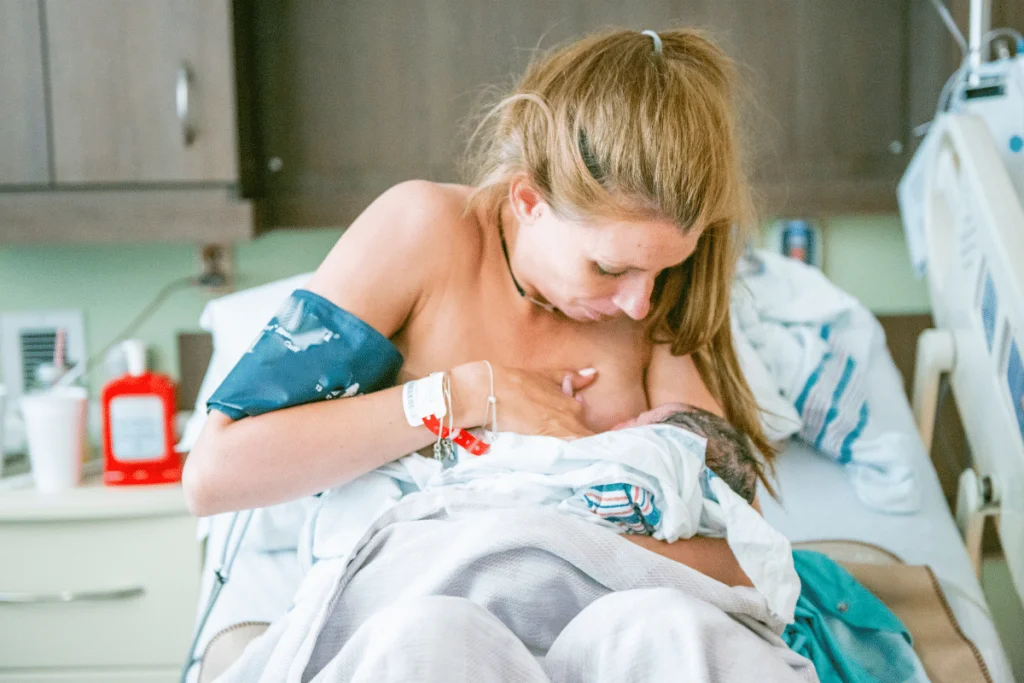 mom in hospital holding breast while breastfeeding newborn