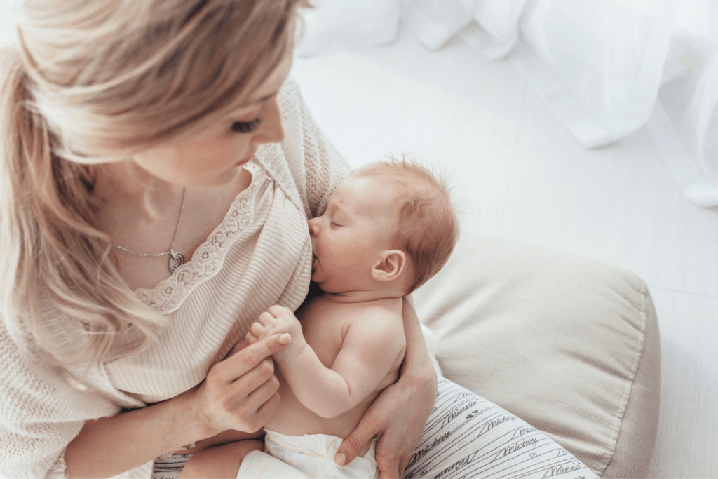 newborn in diaper breastfeeding mom looking down at baby
