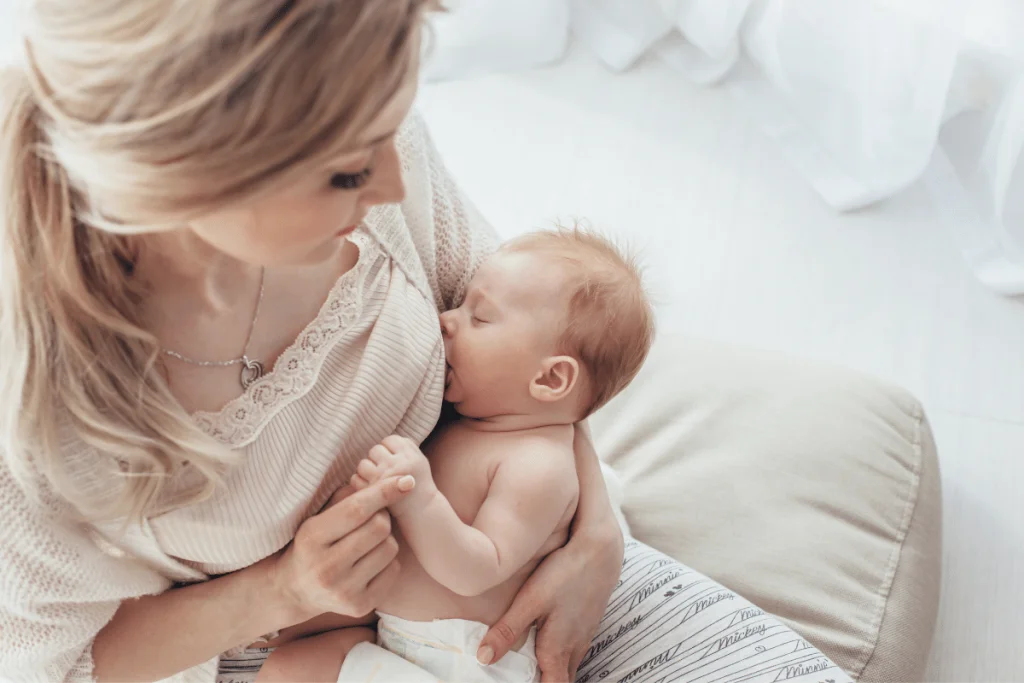 newborn in diaper breastfeeding mom looking down at baby