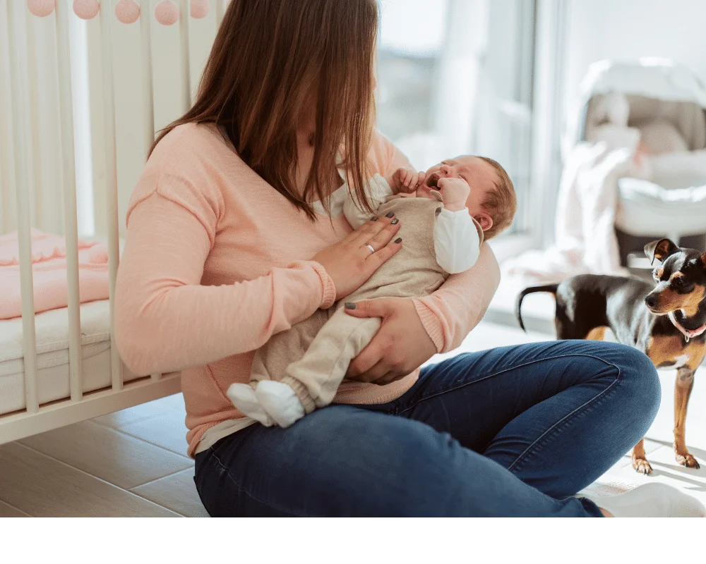 mother sitting in nursery holding crying baby