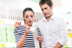 woman and man looking at a long receipt with surprised and worried faces.