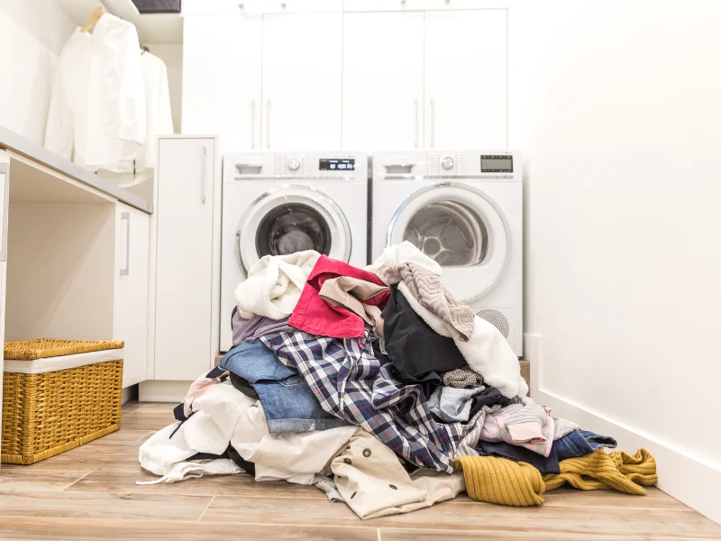 pile of laundry in front of washer and dryer