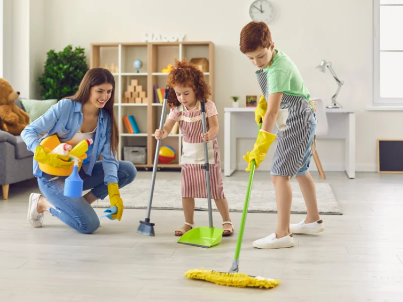 woman and boy and girl cleaning up the living room