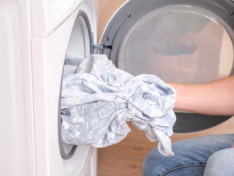 person taking laundry out of front load washer