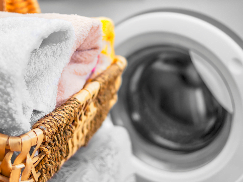 folded laundry in basked in front of front load washing machine