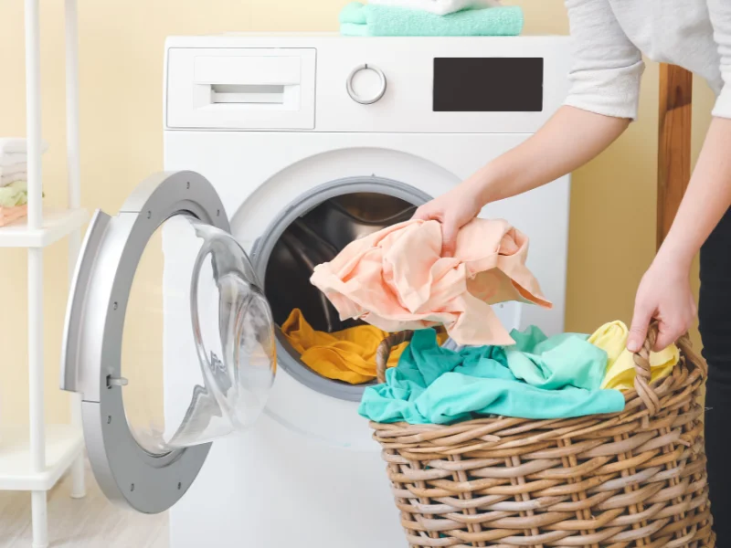 Loading a washing machine from a wicker laundry basket. 