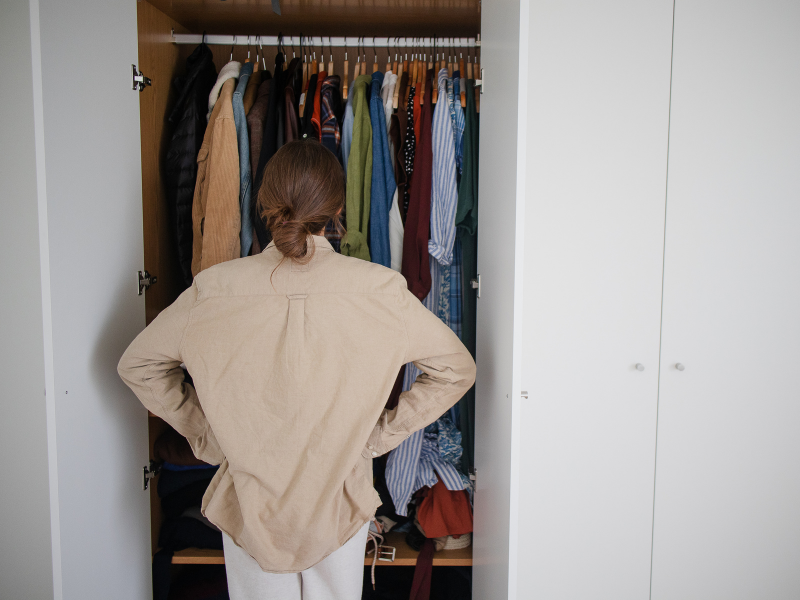 woman with hands on her hips looking into her closet full of clothes