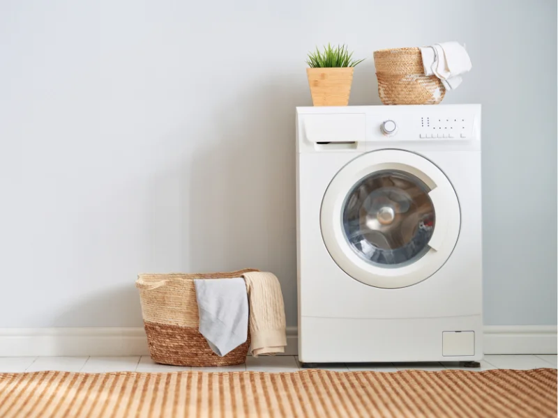 front load washing machine with basket beside and plant and basket on top