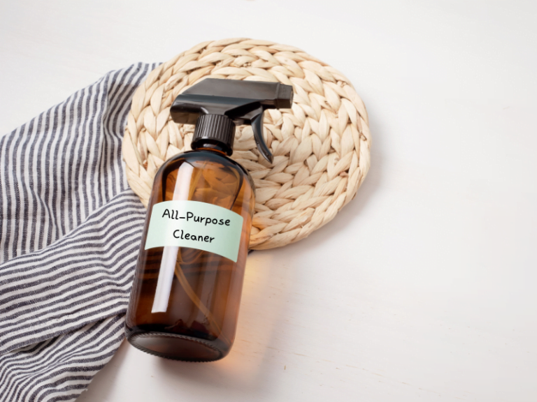 all purpose natural home cleaner in glass amber spray bottle with stripped towel next to it