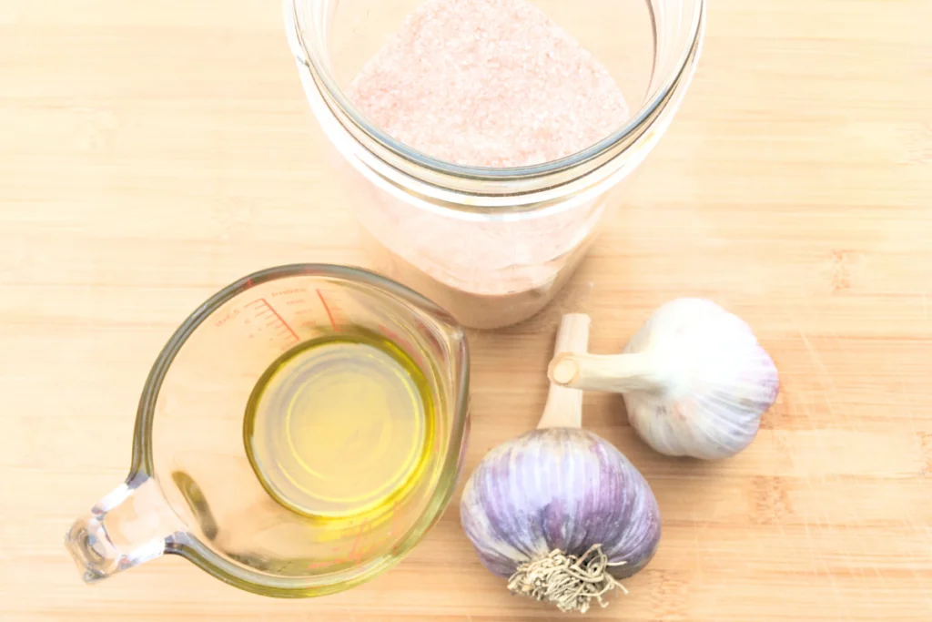 salt, olive oil, and 2 garlic cloves sitting on a counter