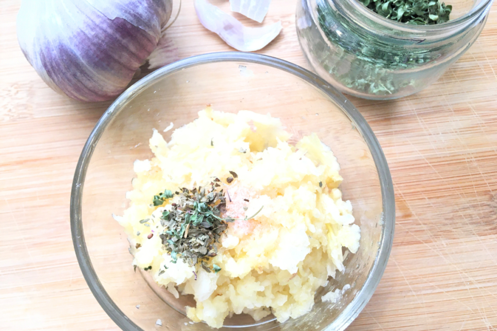 garlic in a glass bowl with salt and herbs