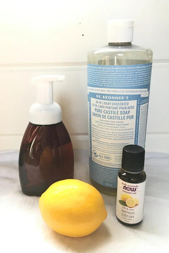 Dr. Bonner's Castile soap, amber foaming soap pump bottle, lemon essential oil, a lemon on a white background with shiplap