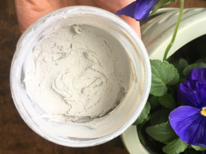 homemade baby diaper rash cream in a mason jar held next to a pot of flowers