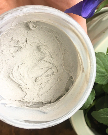 homemade baby diaper rash cream in a mason jar held next to a pot of flowers