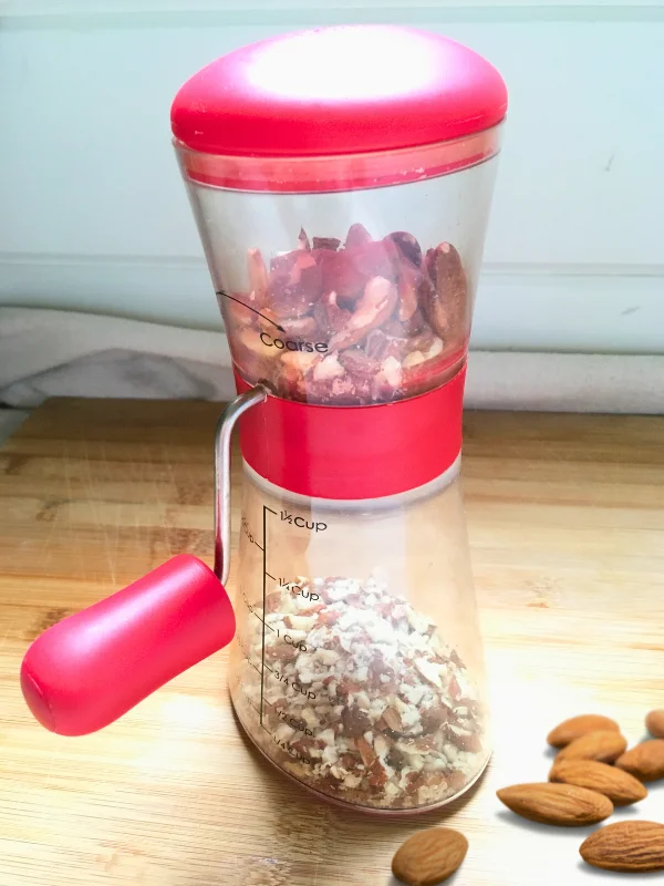 red hand held nut grinder chopping almonds