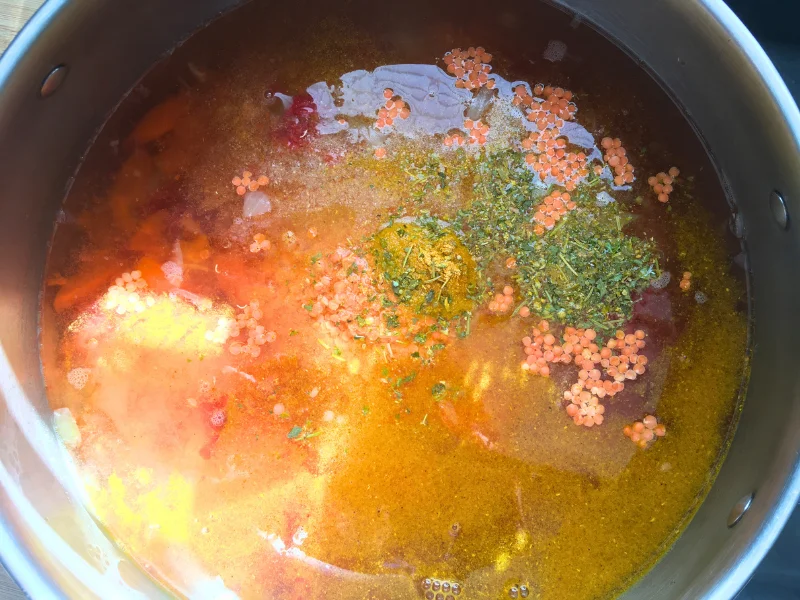 pot with red lentil curry ingredients in it