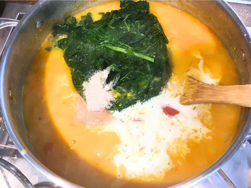 pot with red lentil curry coconut milk, salt and greens on top