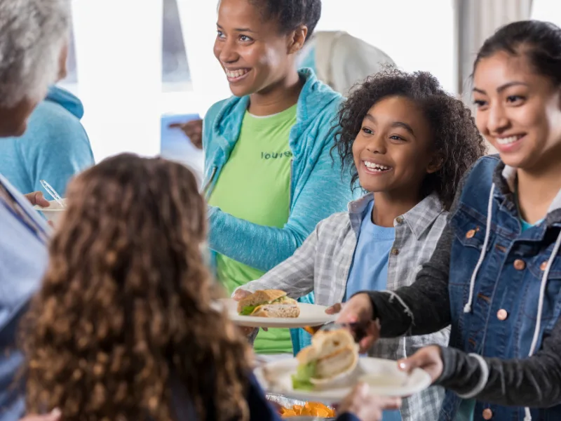 smiling people serving food to other people