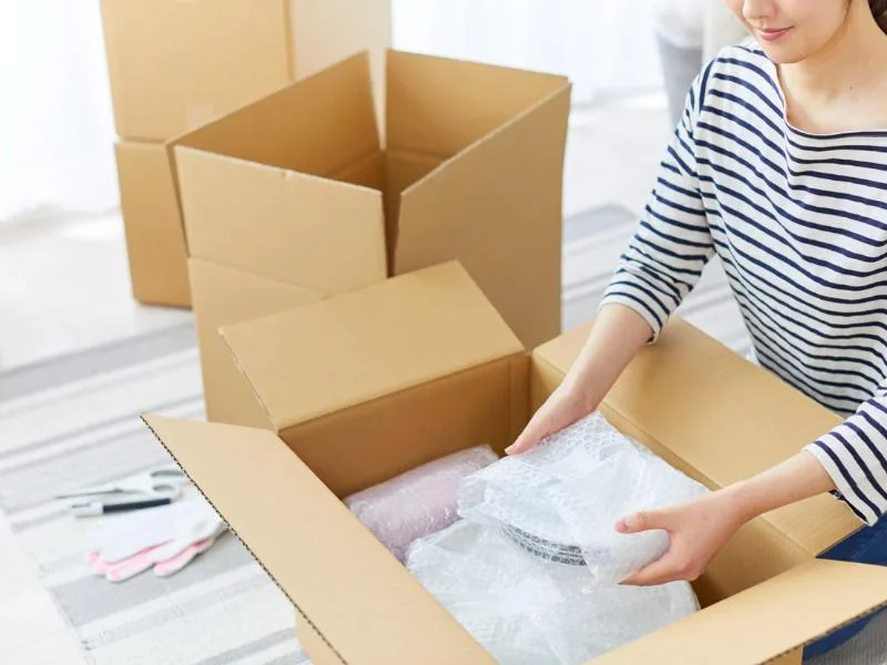 woman putting dishes into cardboard boxes