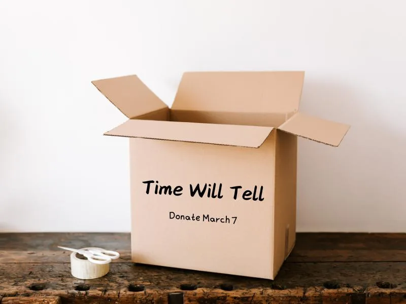 cardboard box on wooden table with scissors and tape beside it. Time Will Tell donate March 7 is written on the box.