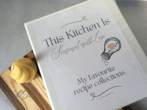 recipe binder on wooden cutting board with beeswax candle