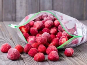 plastic bag of whole frozen strawberries on a wooden table