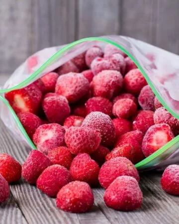 plastic bag of whole frozen strawberries on a wooden table