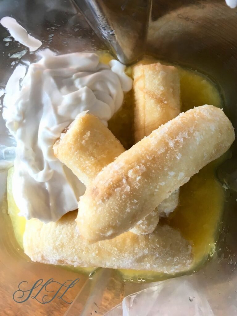 Top view of frozen bananas, coconut and pineapple in blender.