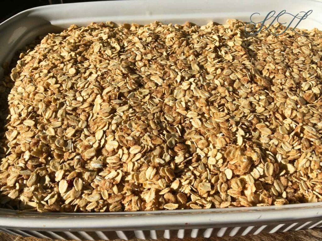 raw vegan apple crisp crumble patted down and ready to bake in white baking dish