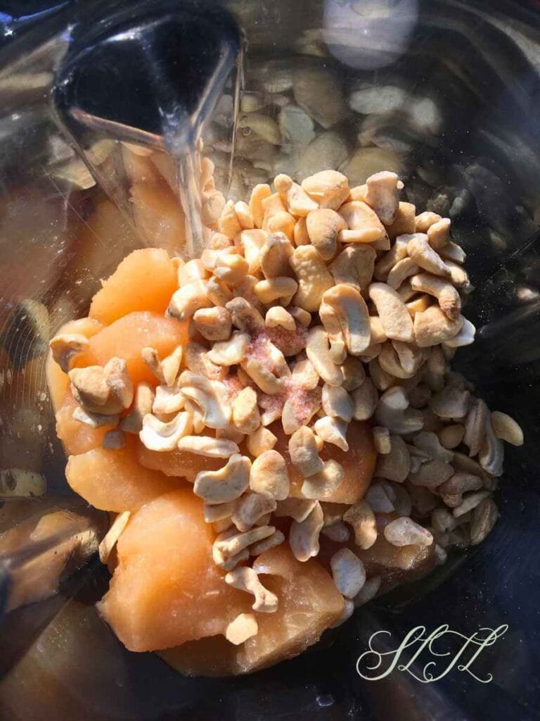 top view of canned pears, raw cashews and salt in a blender